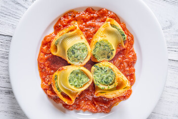 Plated lumaconi stuffed with ricotta and spinach topped with fresh tomato sauce