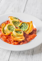 Plated lumaconi stuffed with ricotta and spinach topped with fresh tomato sauce