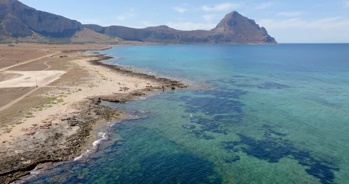 Aerial view of a rocky coastline facing a turquoise sea. It's located in the Zingaro Nature Reserve, near San Vito Lo Capo in Sicily, Italy.