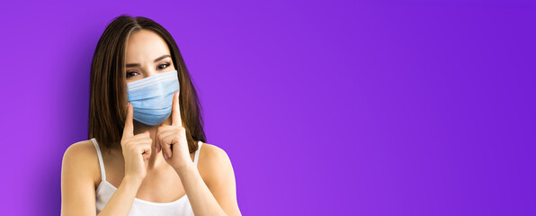 Coronavirus, pandemic, protective concept - brunette hair young woman wearing showing face protection medical mask, isolated violet purple background. Free space sign text area
