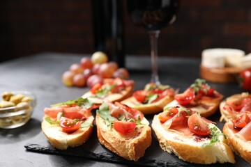 Delicious bruschettas with prosciutto served on black table, closeup