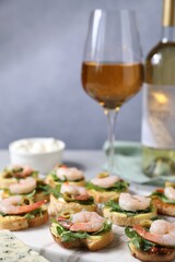 Delicious bruschettas with shrimps and wine on light table