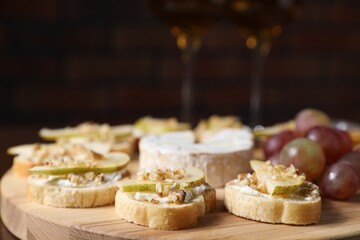 Delicious bruschettas with cream cheese, pears and walnuts served on wooden table, closeup