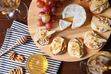 Delicious bruschettas served with camembert, grapes and wine on wooden table, flat lay