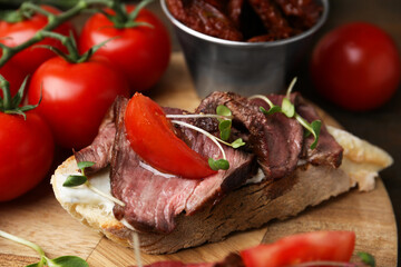 Delicious bruschetta with roast beef served on wooden table, closeup