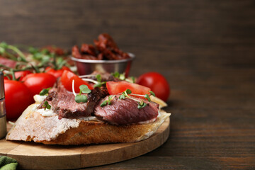 Delicious bruschettas with roast beef served on wooden table, closeup. Space for text