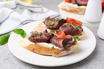 Delicious bruschettas with roast beef served on light table, closeup