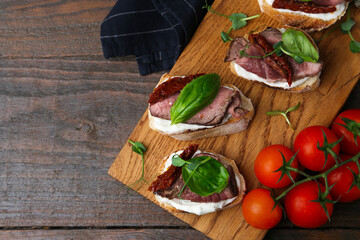 Bruschettas with roast beef served on wooden table, flat lay. Space for text