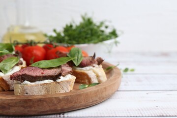 Bruschettas with roast beef served on white wooden table, closeup. Space for text