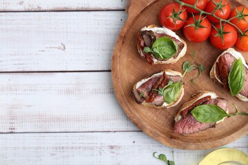 Bruschettas with roast beef served on white wooden table, top view. Space for text