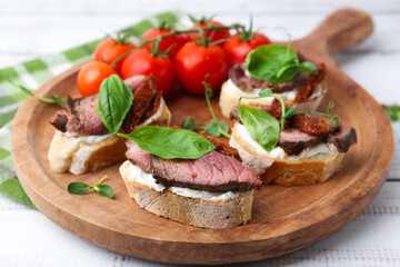 Bruschettas with roast beef served on white wooden table, closeup