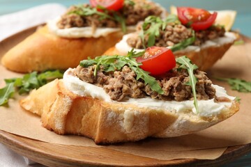 Delicious bruschettas with tuna, cream cheese and tomatoes on table, closeup