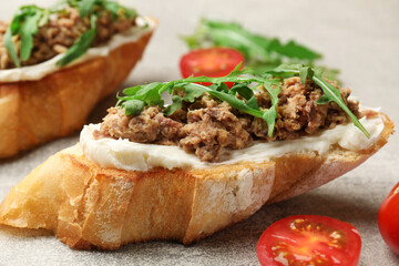 Delicious bruschettas with tuna, tomatoes and arugula on grey table, closeup