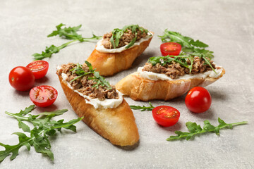 Delicious bruschettas with tuna, tomatoes and arugula on grey table, closeup