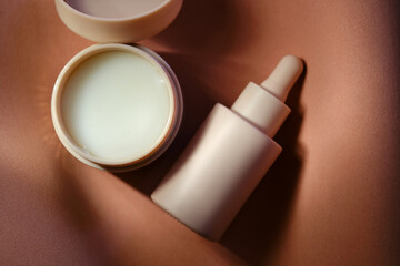 Face cream and serum on a soft beige background.