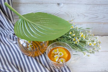 Fresh chamomile tea in a teapot and cup with flowers. Soothing chamomile tea with natural ingredients. 