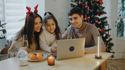 Family enjoying festive time together while watching movie on a laptop during Christmas celebration at home with decorations and food