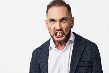 Business professional with intense expression stands against a solid colored background, portraying...