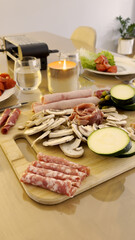 Vertical close-up of Raclette charcuterie and vegetable board with salami and ham.