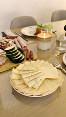 Vertical close-up of layered Raclette cheese plate with candlelight ambiance.
