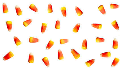 A collection of candy corn pieces with yellow, orange, and white stripes is scattered against a white background. Random Halloween Autumn Thanksgiving Fall Pattern.
