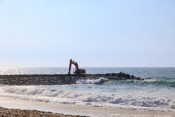 Naklejka premium Excavator working on breakwater at the Atlantic coast, Portugal, Ovar, 8.10.2025