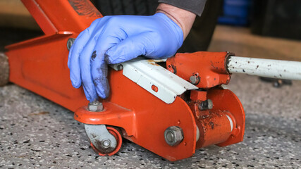 close-up view of a person with a low-profile floor jack for car service work, isolated on a sealed garage floor. automotive design element.