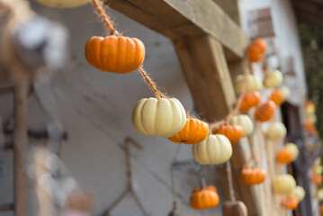 Mini pumpkins hanging on a rustic string garland as autumn home decoration, cozy fall ornament for seasonal or Halloween celebration.
