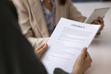 Young businesswoman reading contract on corporate meeting with colleagues