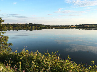 Sunny lake view with light green trees and blue sky. Tranquil landscape perfect for meditation. Breathtaking scenery of rural area Protect the planet Earth. Eco tourism. Travel to remote location