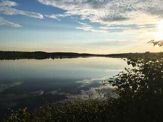 Beautiful sunset over the lake in the evening. Tranquil scenery in the countryside. Deep meditation in the nature. Magical hour of dim soft light for photography. Panoramic view of the pond.