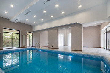 Indoor swimming pool in a spacious and bright room with large windows. Clean lines and...
