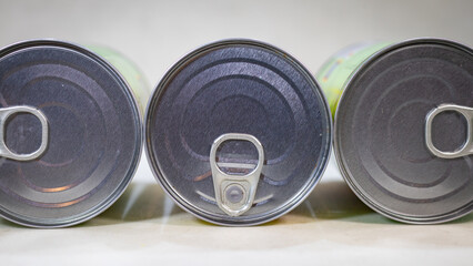 Three food tin cans lying sideways with ring‑pulls close‑up, product packaging still life