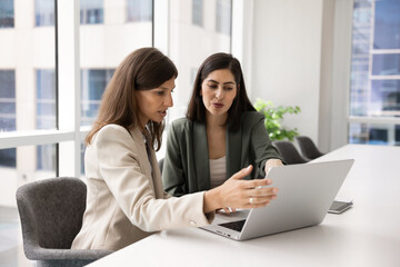 Diverse young female colleagues working on project together