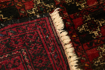Hand-knotted Persian or Afghan wool rug detail, red and black tribal pattern, fringe edge
