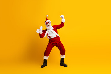 Cheerful Santa Claus in a festive celebration pose against a vibrant yellow background, embodying...