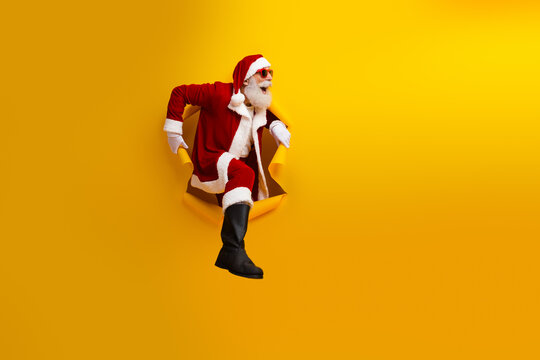 Santa Claus bursting through a yellow background showcasing festive cheer and holiday magic in a creative and charismatic pose