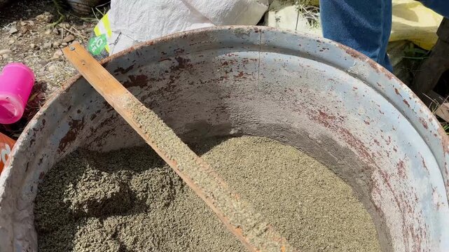 Close-up of wooden sieve over metal bucket with coarse and fine sand
