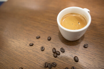Cup of espresso coffee with coffee beans on the table, Artistic selective focus