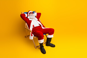 Cheerful Santa Claus relaxing in a deck chair against a vibrant yellow background, enjoying a fun...