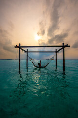 Tranquil closeup calm sea water waves with palm trees. Model sitting on hammock. Tropical island beach landscape exotic shore coast. Summer vacation, holiday amazing nature. Relax paradise, Maldives.