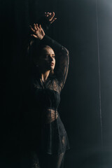 A mysterious woman stands in silhouette against a bright window, surrounded by dramatic smoke and shadows