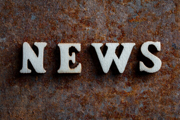 Wooden letters with the word news on an old rusty surface, closeup, top view. The concept of media...