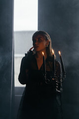 A mysterious woman stands in silhouette against a bright window, surrounded by dramatic smoke and shadows