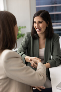 Happy Latin business consultant woman shaking hands with female coworker