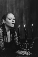 Mysterious young woman in black lace gazes intensely through candlelight, evoking elegance and...