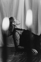 Mysterious young woman in black lace gazes intensely through candlelight, evoking elegance and gothic allure