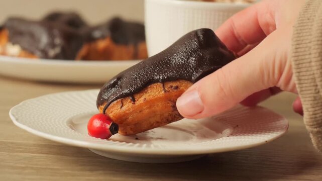 hand holding up a piece of a chocolate eclair that has been broken open, clearly revealing the light cream or custard filling inside