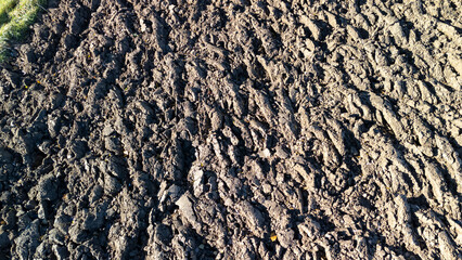 Close-up of textured soil surface showing dried cracks and furrows, reflecting agricultural earth conditions. Ideal for themes of farming and nature.