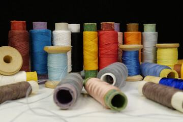 Spools with multi-colored threads on black background, close-up shot